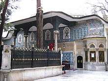 Photo of old two-storey building covered in blue Iznik tiles, with a prostyle portico and windows on the upper storey