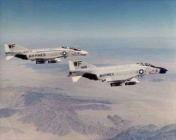 A pair of armed Phantom jet fighters in flight at high altitude