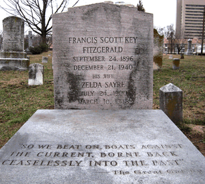 A color photograph of a grave. The headstone reads Francis Scott Key Fitzgerald September 24, 1896 December 21, 1940 His Wife Zelda Sayre July 24, 1900 March 10, 1948. "So we beat on boats against the current, borne back ceaselessly into the past" -- The Great Gatsby