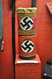 Two red armbands bearing swastikas, mounted on a stand