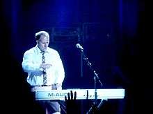 A man in a shirt and tie playing a keyboard on stage