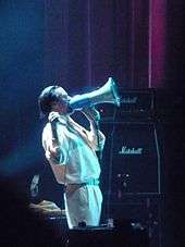 A man dressed in white singing through a megaphone