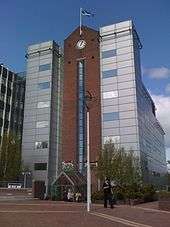 Six-storey office building with facing brick, glass and silver cladding with clock feature.