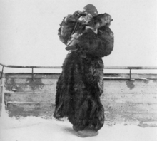 A woman dressed in thick fur uses binoculars.