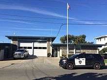 A fire station with an American flag and a police SUV in front