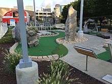 A miniature golf course with putting greens with art installations such as rock formations and brightly-painted guitars
