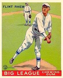 A baseball card of a man wearing a white baseball uniform with blue trim standing on a pitcher's mound after throwing a ball.