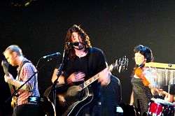 A color photograph of members of the Foo Fighters on stage with instruments