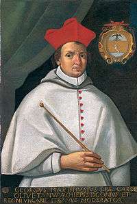 Priest dressed in white, in a cardinal's red hat