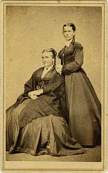 Two women—the older one seated and the younger one standing