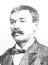 Head of a white man with mustache wearing a suit and bow tie.