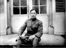 A man in a military uniform, sitting on a bench.