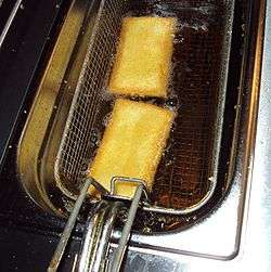 Two parcels of pastry being lowered in a basket into oil