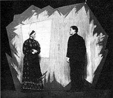 A black-and-white photo of a man and woman on a stage