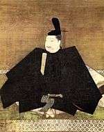 Portrait in three-quarter view of a person seated on the floor in courtly attire carrying a stick like object.