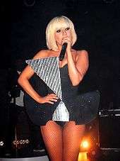 Lady Gaga in a short dress singing with a microphone in left hand