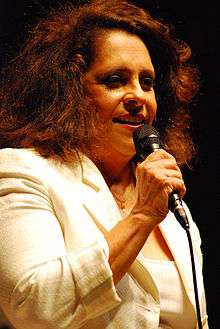 A woman in a white dress is holding a microphone.