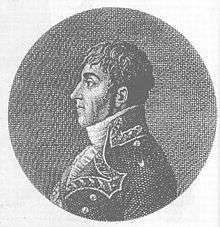 Black and white print depicts the head and shoulders of a wavy-haired man looking to the viewer's left. He wears a dark military coat.