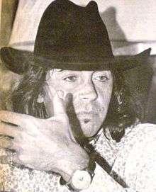 A man with long hair is wearing a cowboy