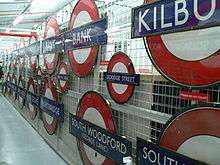 A collection of London Underground roundels from many stations displayed on a wire mesh screen