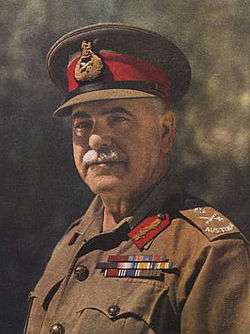 Head and shoulders colourised photograph of General Sir Thomas Blamey, KCB, CMG, DSO taken circa 1942. Blamey has a grey moustache and is wearing a peaked cap with scarlet cap band and general's bullion cap badge and an Australian Army khaki shirt to which are attached Australian general's embroidered rank slides, general's gorget patches in scarlet with gold bullion oakleaves and three ribbon bar rows for his various orders, decorations and medals.