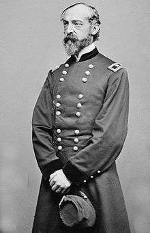 Man standing with gray beard and facing left in uniform with two vertical columns of buttons