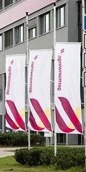 A closeup of three tall flags marked with the Germanwings logo, each at half-mast