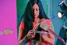 Gingger Shankar—an Indian woman in a black dress and black boots, with long black hair—plays 10-string violin onstage.