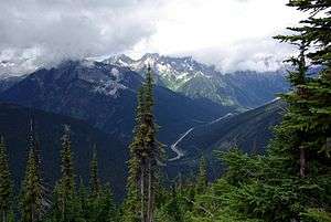 A forested valley under misty peaks, with the Trans-Canada Highway running through