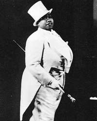 A black-and-white photo of Bentley in a white tux with tails, holding a cane and wearing a tophat