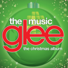 The word "Glee" is in large lowercase red print and centered on a green background with a Christmas bauble. Beneath it are the words "The Christmas Album" and above are "The Music", both in lowercase white font.