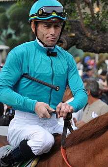 a jockey wearing turquoise racing silks