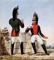 Two French dragoons in green coats with madder red facings, white breeches, brass helmets, and black knee boots