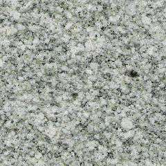 The polished face of a granite slab showing an even pattern of white, greenish and black crystals.