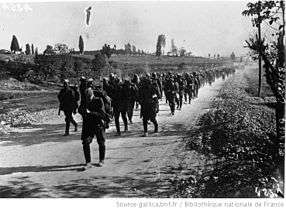 Soldiers marching down a road