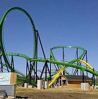 Green-and-yellow roller-coaster track against blue sky
