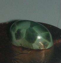 A polished cabochon of green pumpellyite showing the desirable chatoyant, cell-like structure found in the Michigan material.