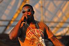 Gucci Mane performing in Williamsburg, Brooklyn on August 29, 2010. He is rapping into his microphone.