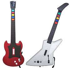 A photograph of two guitar-shaped video game controllers side-by-side, the left one red and the right one white all on a solid, white background