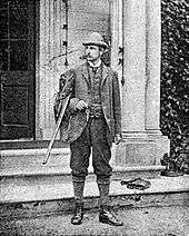 Young Rider Haggard standing at the steps of an English country house with a hunting gun uncocked in his arm