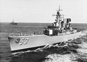 Black-and-white photograph of a destroyer escort with the number "53" painted on the bow. The ship is underway. A second ship of a similar design is in the background.