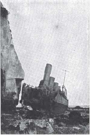 HMS Nubian, a destroyer, beached near cliffs with her bow blown off by a torpedo.