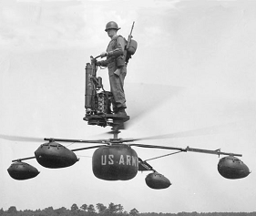 An infantryman in khaki uniform and steel helmet, a rifle slung on his back, stands atop a platform mounted above two counter-rotating rotors and four landing-gear legs of a strange helicopter-like craft, holding the steering handlebars of the vehicle.