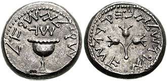 Two sides of a silver coin with the coin shown on the right containing a depiction of a chalice or cup and the coin face shown on the left depicting a priestly staff topped by 3 almond blossums