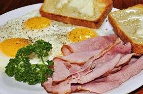 Ham and eggs served with thinly-sliced ham and fried eggs prepared "sunny side up".