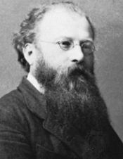 black and white Victorian photograph of the head and shoulders of a bespectacled man with a large dark beard