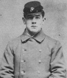 Head and torso of a young white man wearing a forage cap and a heavy double-breasted coat with two columns of buttons down the chest.