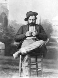 Man with beard in dungy clothes leaning back in a chair