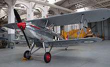 a colour photograph of a biplane in UK markings in a museum