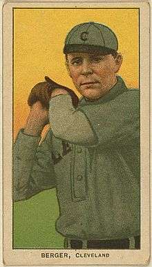 A baseball card of a man wearing a gray baseball uniform with a black "C" on the cap holding his hands raised to the side of his head wearing a baseball glove on his left hand.